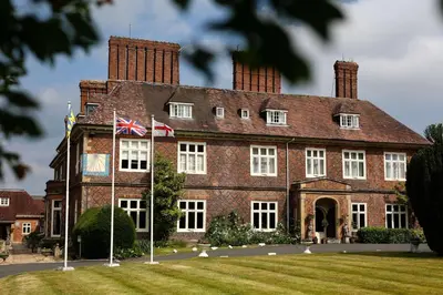 a large brick building with two flags in front of it at Albrighton Hall Hotel and Spa, a member of Radisson Individuals in Shrewsbury