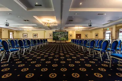 a conference room with blue chairs and a projection screen at Albrighton Hall Hotel and Spa, a member of Radisson Individuals in Shrewsbury