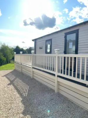 a white fence next to a mobile home at Weston pools lodge in Oswestry