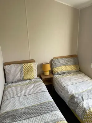 a room with two beds and a table with a lamp at Weston pools lodge in Oswestry