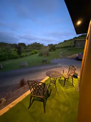 a patio with two chairs and a table on the grass at Sea Breeze Lodge in Aberaeron