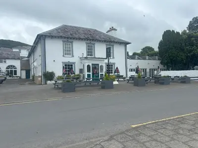 a white building with benches in front of it at Feathers Hotel Bar and Restaurant in Aberaeron