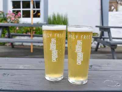 two glasses of beer sitting on a wooden table at Feathers Hotel Bar and Restaurant in Aberaeron