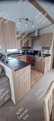 a kitchen with wooden cabinets with white writing on it at Kyffin 643 in Barmouth
