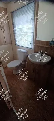 a bathroom with a toilet and a sink and a window at Kyffin 643 in Barmouth