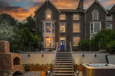 a large house with a bath tub in front of it at Eryri Snowdonia Premier Family Retreat with Hot Tub and Fire Pit in Dolgellau