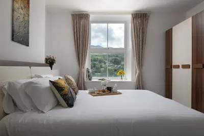 a bedroom with a large white bed with a window at Eryri Snowdonia Premier Family Retreat with Hot Tub and Fire Pit in Dolgellau