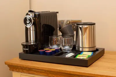 a counter with a coffee maker and glasses on it at The Castle Coaching Inn in Trecastle