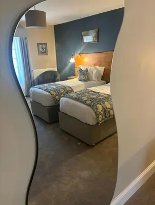 a hotel room with two beds and a mirror at The Castle Coaching Inn in Trecastle