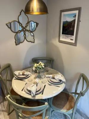 a dining room table with chairs and a light fixture at Posh Little Cottage in Llangollen