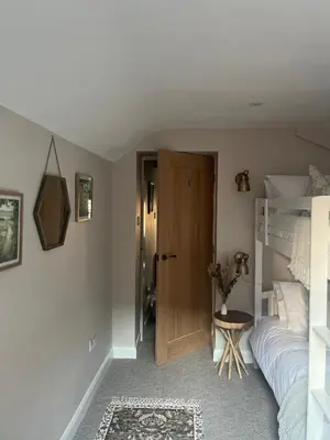 a bedroom with a bed and a wooden door at Posh Little Cottage in Llangollen