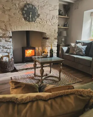 a living room with a table and a fireplace at Posh Little Cottage in Llangollen