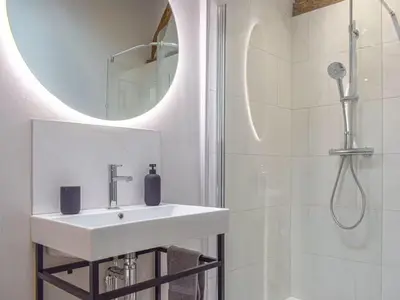 a white bathroom with a sink and a shower at Castle Beams in Craven Arms