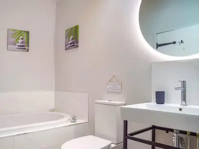 a bathroom with a sink and a toilet and a tub at Castle Beams in Craven Arms