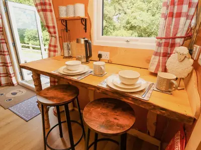 a wooden table with cups and saucers on it in a kitchen at Shepherd's Cwtch in Llandovery