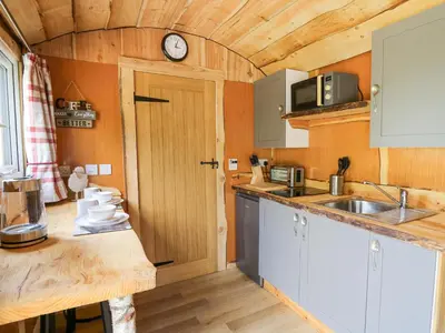 a kitchen with a sink and a clock on the wall at Shepherd's Cwtch in Llandovery