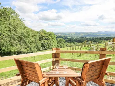 a wooden table and chairs on a balcony with a view at Shepherd's Cwtch in Llandovery