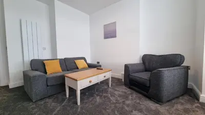 a living room with two chairs and a coffee table at Abergwaun Apt 2 in Aberystwyth