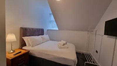 a small bedroom with a bed with a lamp and a window at Abergwaun Apt 3 in Aberystwyth