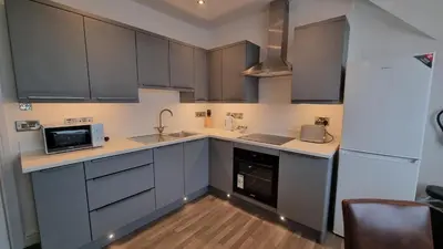 a kitchen with gray cabinets and a white refrigerator at Abergwaun Apt 3 in Aberystwyth
