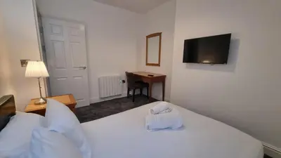a bedroom with a white bed with a television on the wall at Abergwaun Apt 3 in Aberystwyth