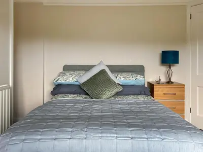 a bedroom with a bed and a night stand with a lamp at Mum's Place in Hay-on-Wye