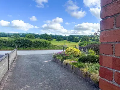 an empty road with a brick wall and flowers at Mum's Place in Hay-on-Wye