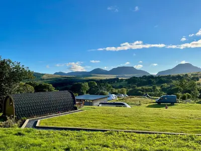 a field with a barn and mountains in the background at MTB Jumps View Pod in Trawsfynydd