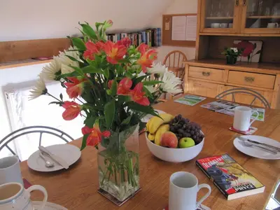 a vase with flowers and a bowl of fruit on a table at Tollant in Rhayader