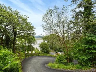 a winding road with trees on either side at High Tide in Scyborycoed