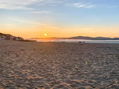 a beach with the sun setting in the distance at High Tide in Scyborycoed