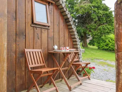 two chairs and a table in front of a cabin at Oak View in Llangadog