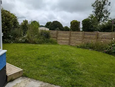 a backyard with a fence and a green yard at Synod Farm Cottage, 5 Person Hot Tub, Pets Welcome in Llandysul