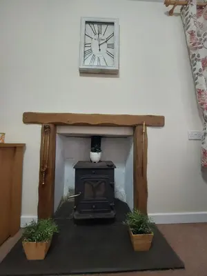 a fireplace with a stove and a clock on the wall at Synod Farm Cottage, 5 Person Hot Tub, Pets Welcome in Llandysul