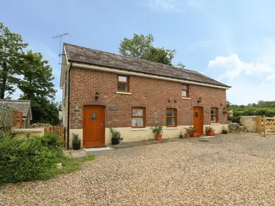 a brick house with orange doors on a gravel driveway at Garden View in Llanybydder