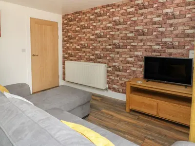 a living room with a tv and a brick wall at Garden View in Llanybydder