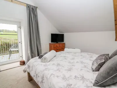 a bedroom with a bed and a television and a window at Field View in Llanybydder