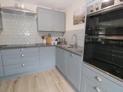 a kitchen with white cabinets and a black oven at Pennant Tigi Uchaf in Dolgellau