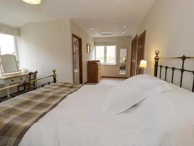a bedroom with a large bed with white sheets at Pennant Tigi Uchaf in Dolgellau