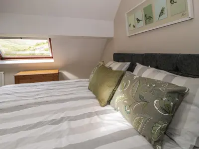 a bedroom with a bed with white sheets and a window at Pennant Tigi Uchaf in Dolgellau
