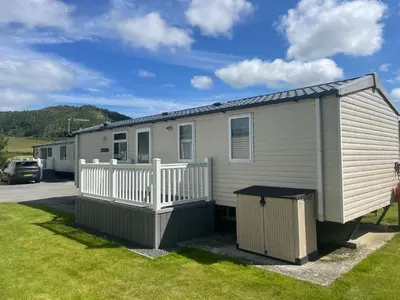 a mobile home with a porch and a fence at Cozy 2 Bedroom Static Caravan in Clarach Bay , Aberystwyth in Aberystwyth