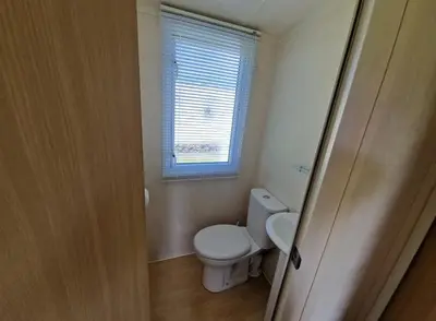 a small bathroom with a toilet and a window at Cozy 2 Bedroom Static Caravan in Clarach Bay , Aberystwyth in Aberystwyth