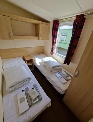 a small room with two beds and a window at Cozy 2 Bedroom Static Caravan in Clarach Bay , Aberystwyth in Aberystwyth