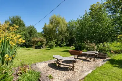 a garden with a bench and a bowl on a table at Daisys Place at Middle Farm and Cottages in Picklescott