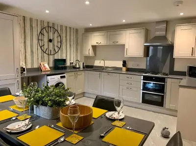a kitchen with a dining table and a kitchen with white cabinets at The Stokesay Ludlow in Ludlow