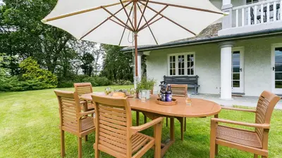 a wooden table and chairs with an umbrella at Hafod Cae Maen in Penrhyndeudreath