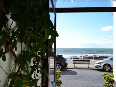 a building with a view of the beach and a bench at Cardigan and Celtic Bay Guest House - Self Catering Accommodation in Aberystwyth