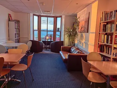 a waiting room with tables and chairs and a library at Cardigan and Celtic Bay Guest House - Self Catering Accommodation in Aberystwyth