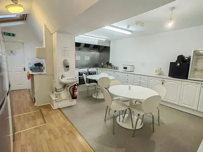 a kitchen with white tables and chairs in it at Cardigan and Celtic Bay Guest House - Self Catering Accommodation in Aberystwyth