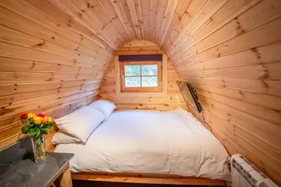 a bed in a log cabin with a window at Ocean View with hot tub in Barmouth